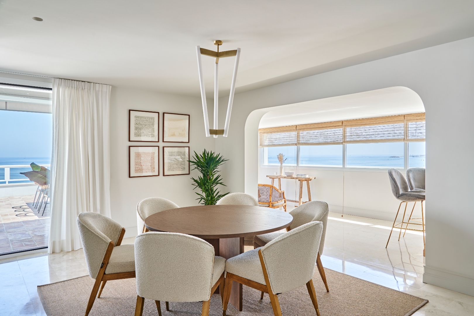 Dining room — round table, boucle chairs, sea window, arch leading to bar