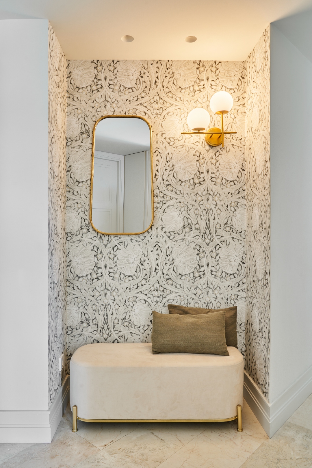 Entrance hallway at Terraza Del Sol — botanical wallpaper, velvet bench, gold mirror, globe sconce