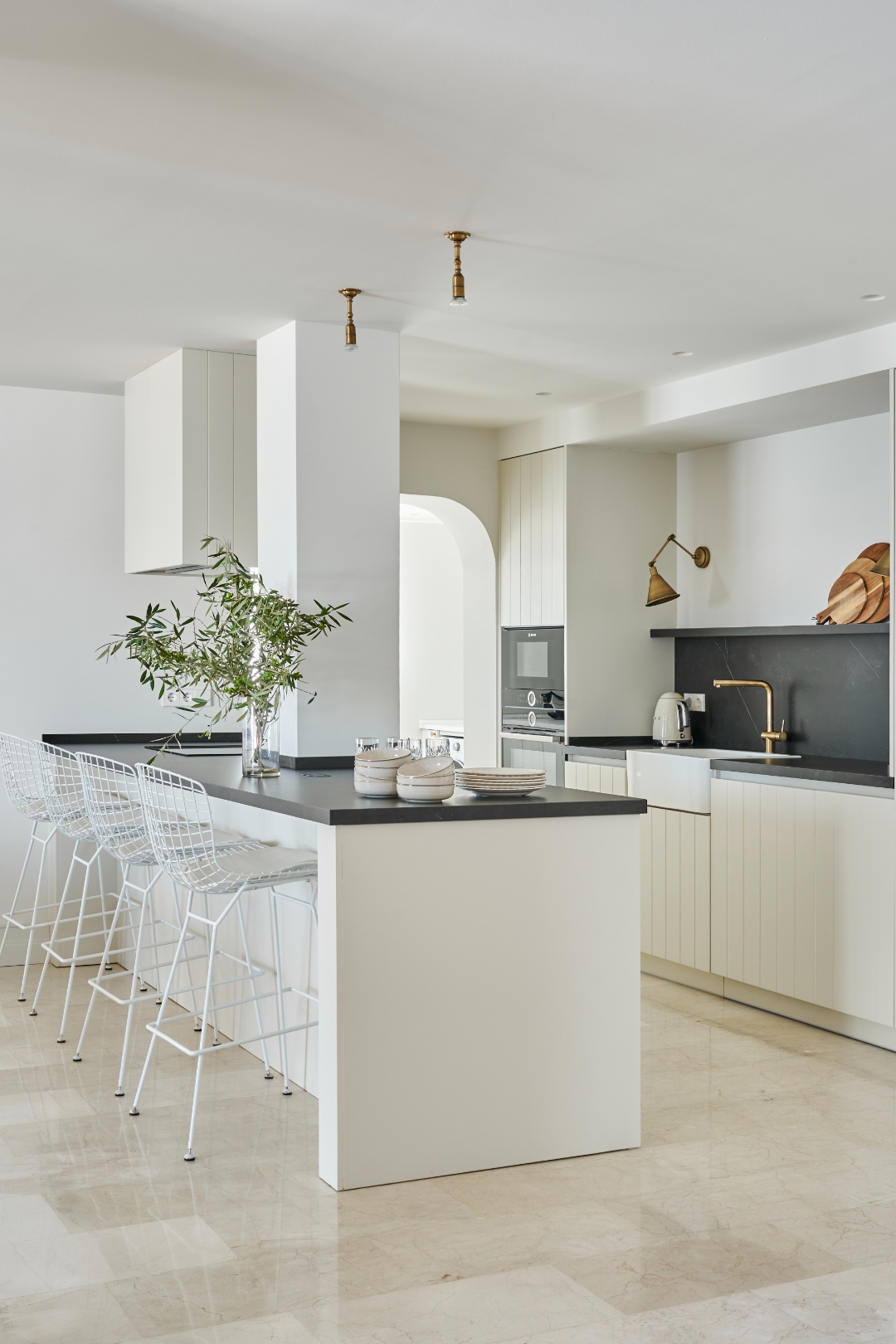 Kitchen — full view, island, marble floor, arch detail, brass pendant