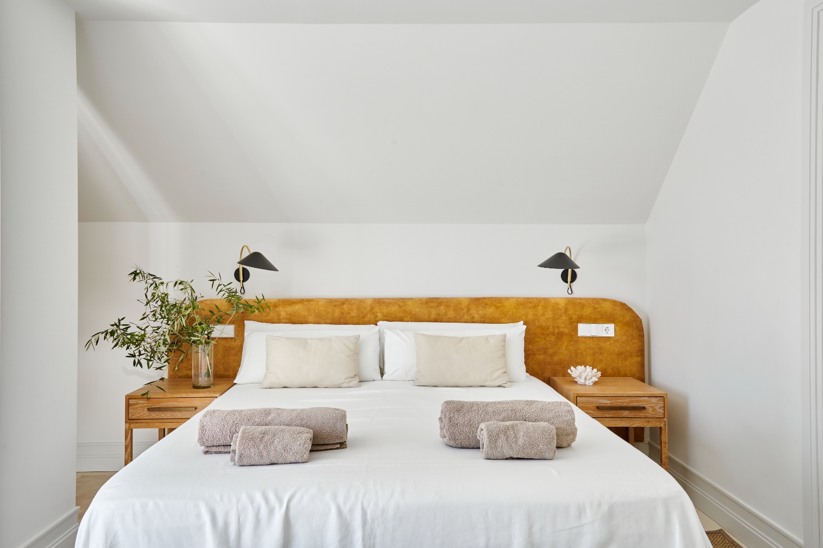Master bedroom — amber headboard, black sconces, white linen