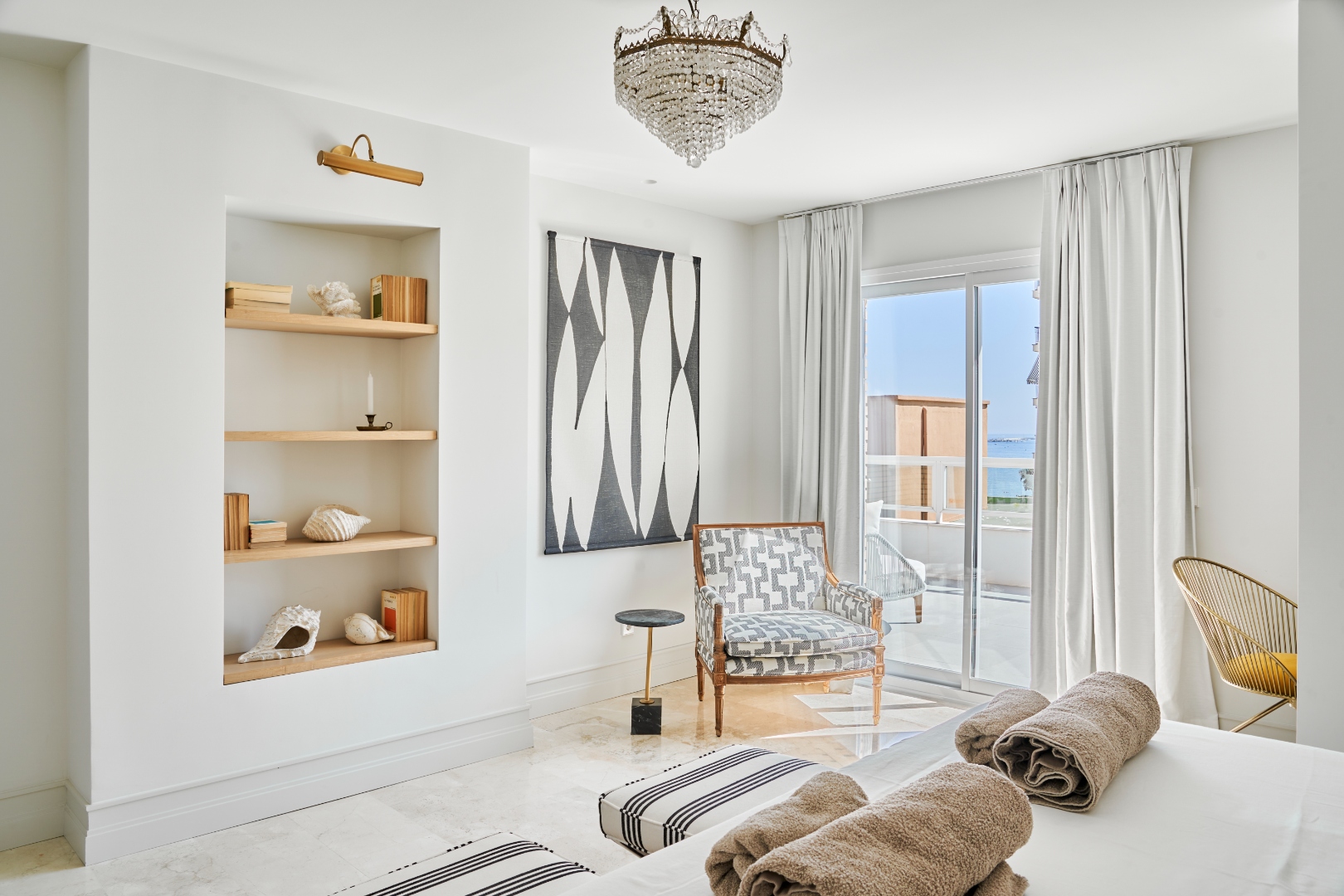 Master bedroom — chandelier, shelving, art, terrace door open to sea