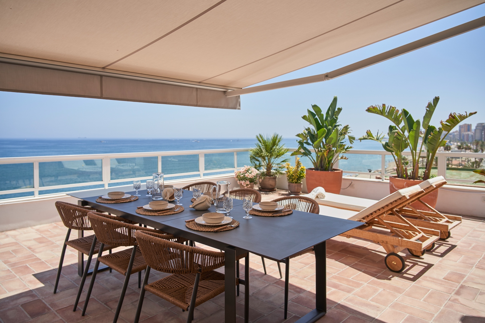 Terraza Del Sol terrace — dining table for six, sun lounger, tropical plants under awning
