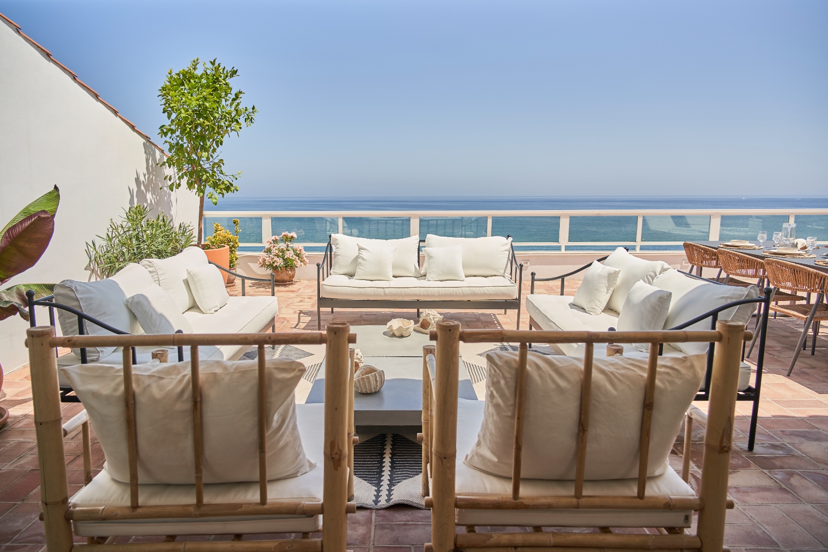 Terraza Del Sol terrace dining — rattan chairs, linen napkins, sea and pink flowers