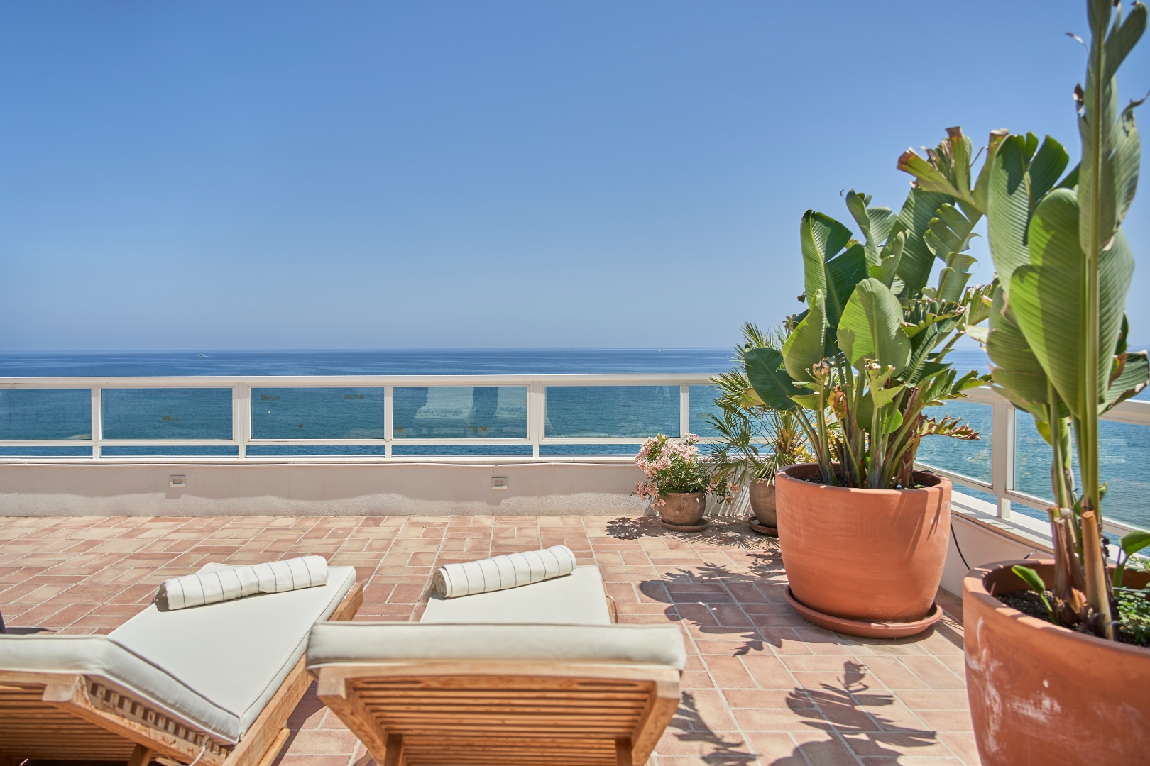 Sun loungers on Terraza Del Sol terrace — terracotta planters, open sea