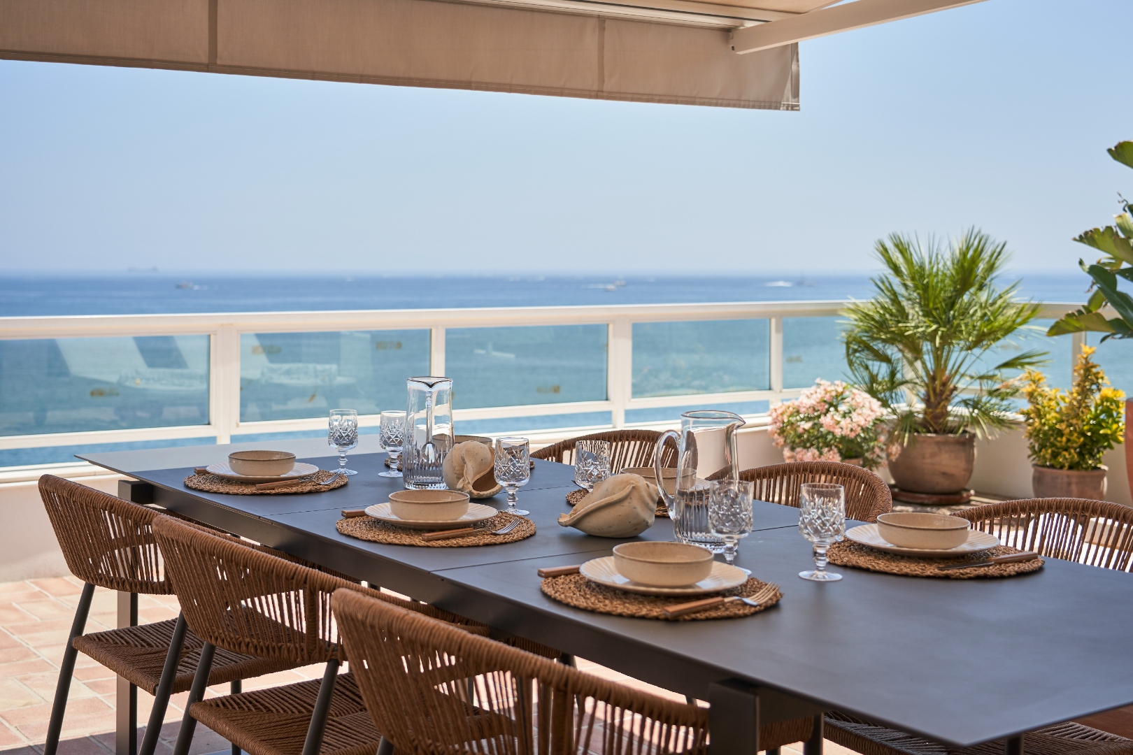 Terrace table detail — crystal glasses, linen napkins, sea beyond